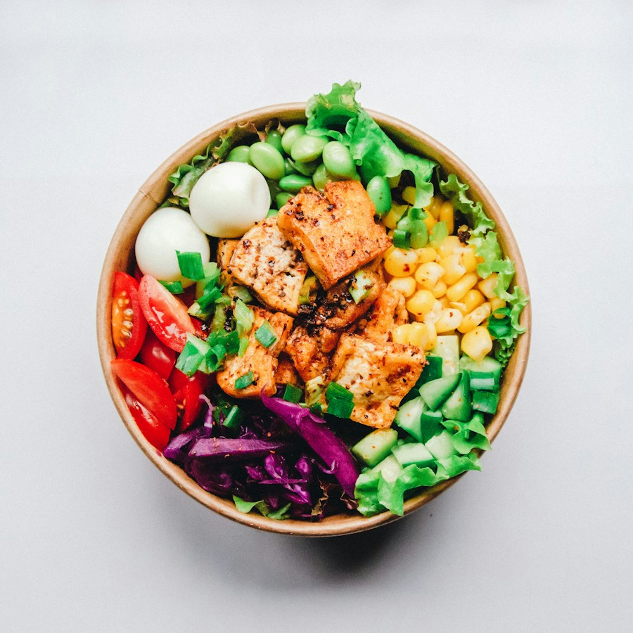 A colorful bowl of fresh vegetables, tofu, and greens